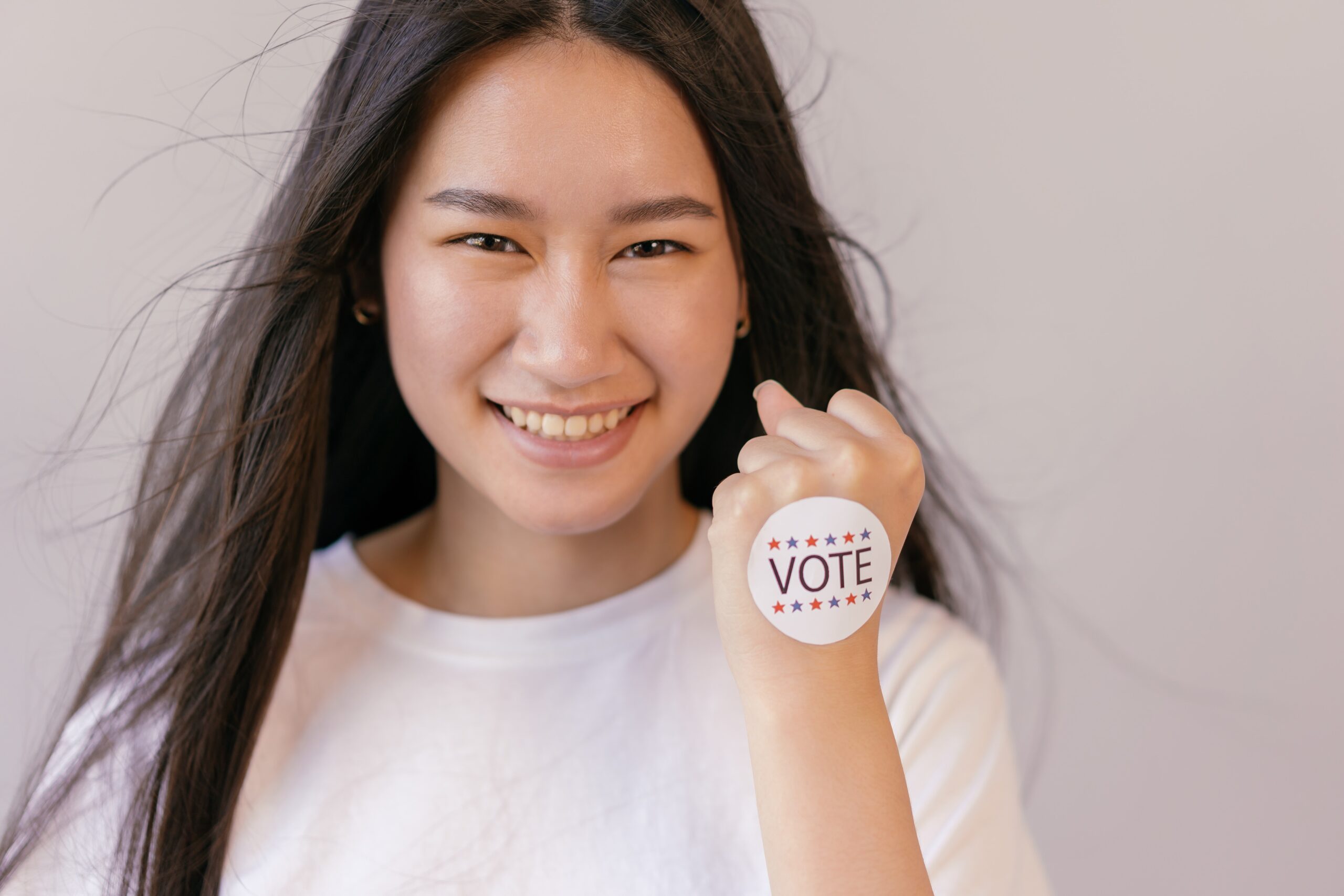 pexels-mikhail-nilov-vote-sticker Young women with sticker on hand that says "VOTE"